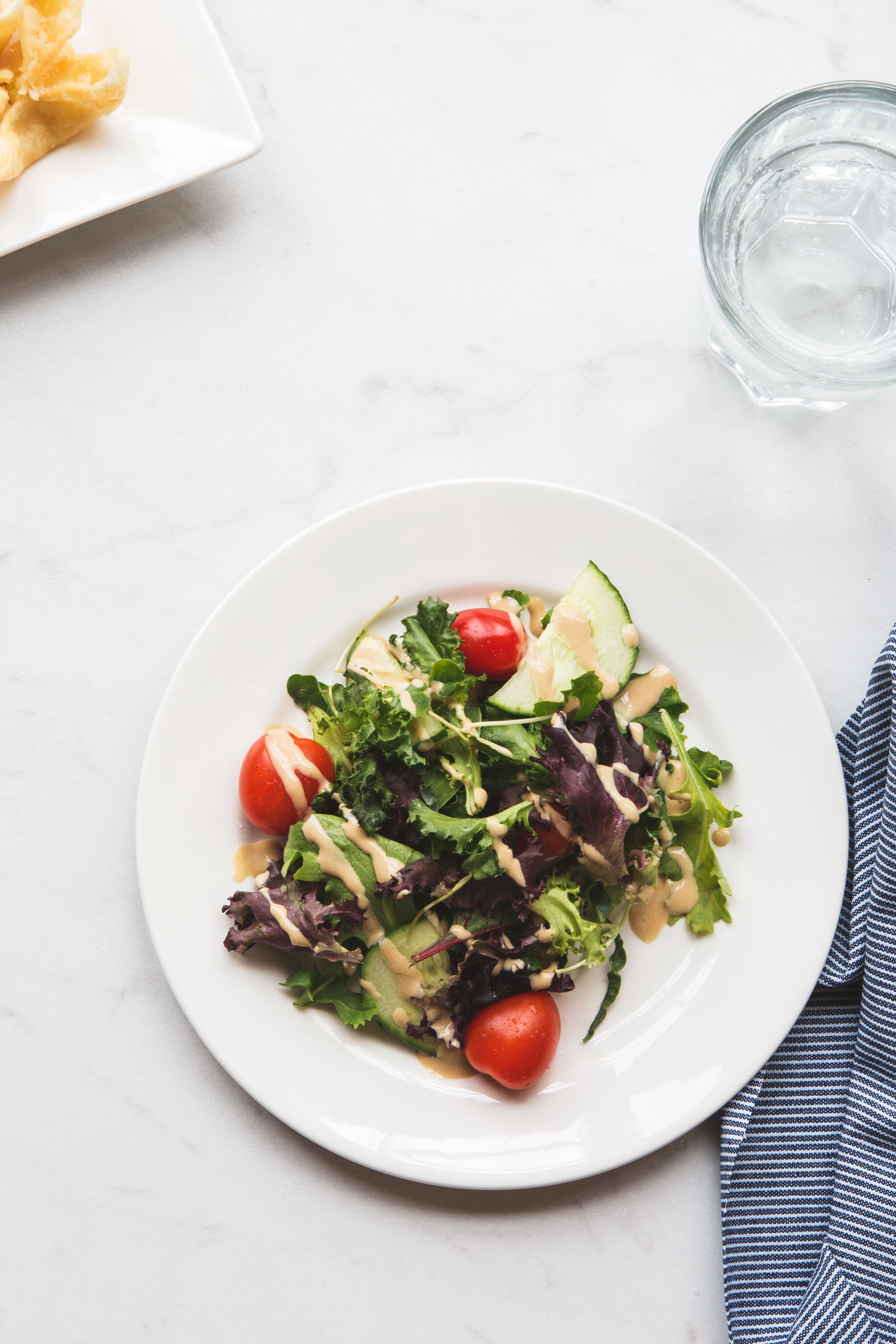 Fresh garden salad with cherry tomatoes, cucumbers, and dressing on a white plate